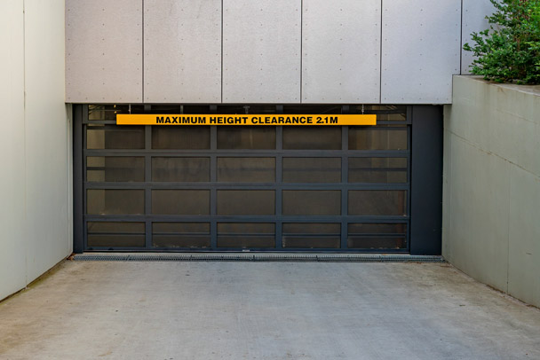 Dark sectional commercial door fitted to a covered parking entrance