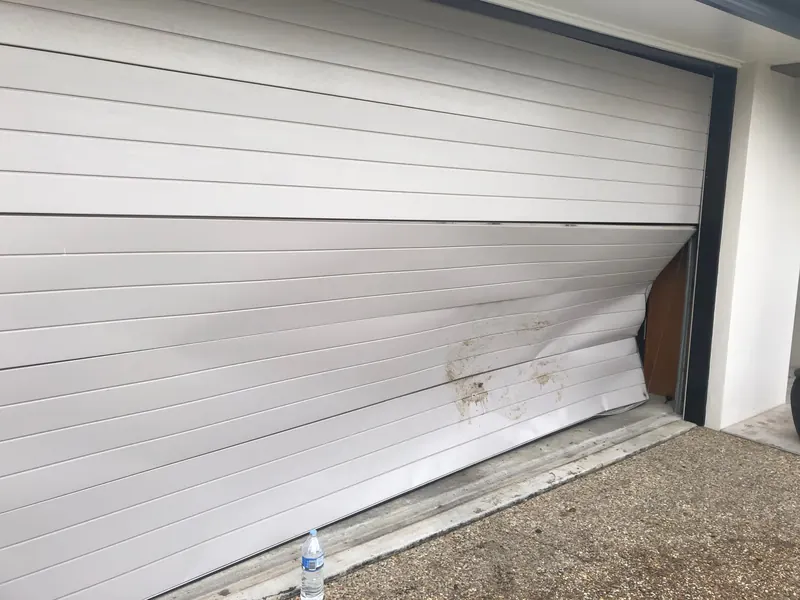 Garage door with a damaged lower panel needing repair