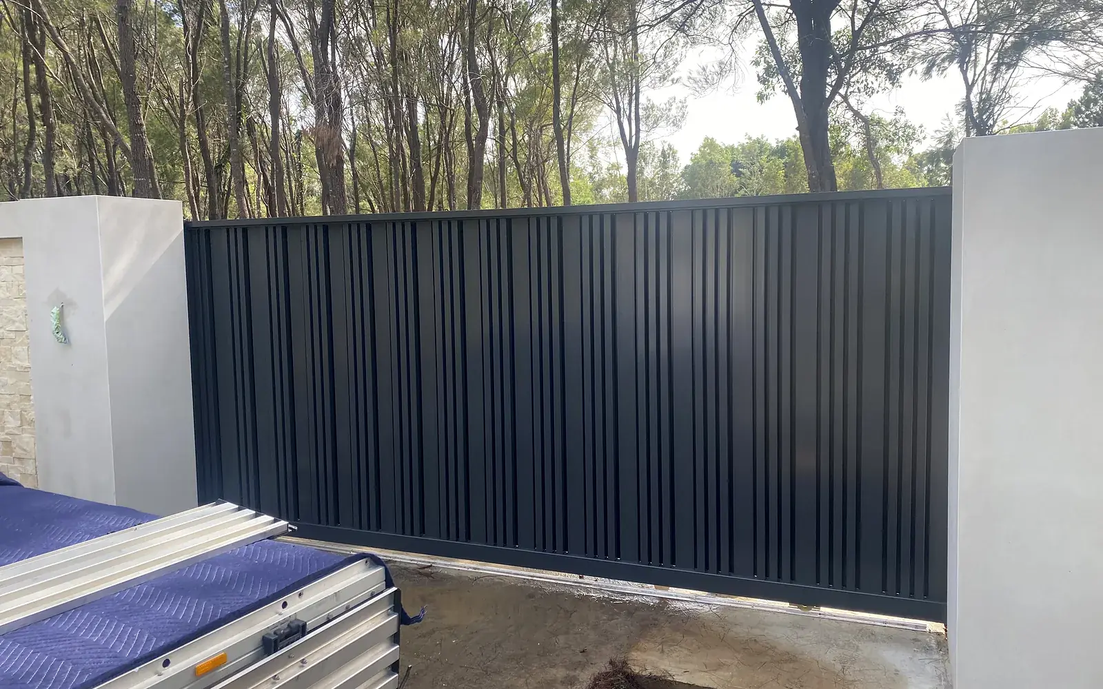 Sliding driveway gate with vertical panels across the entrance