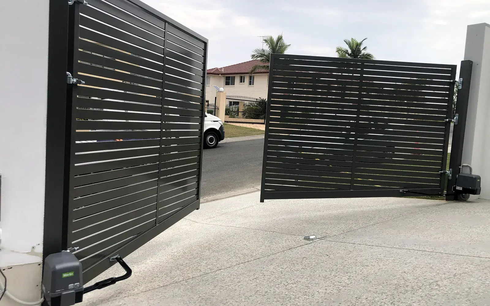 Automated swing gate with two hinged leaves at a driveway entrance